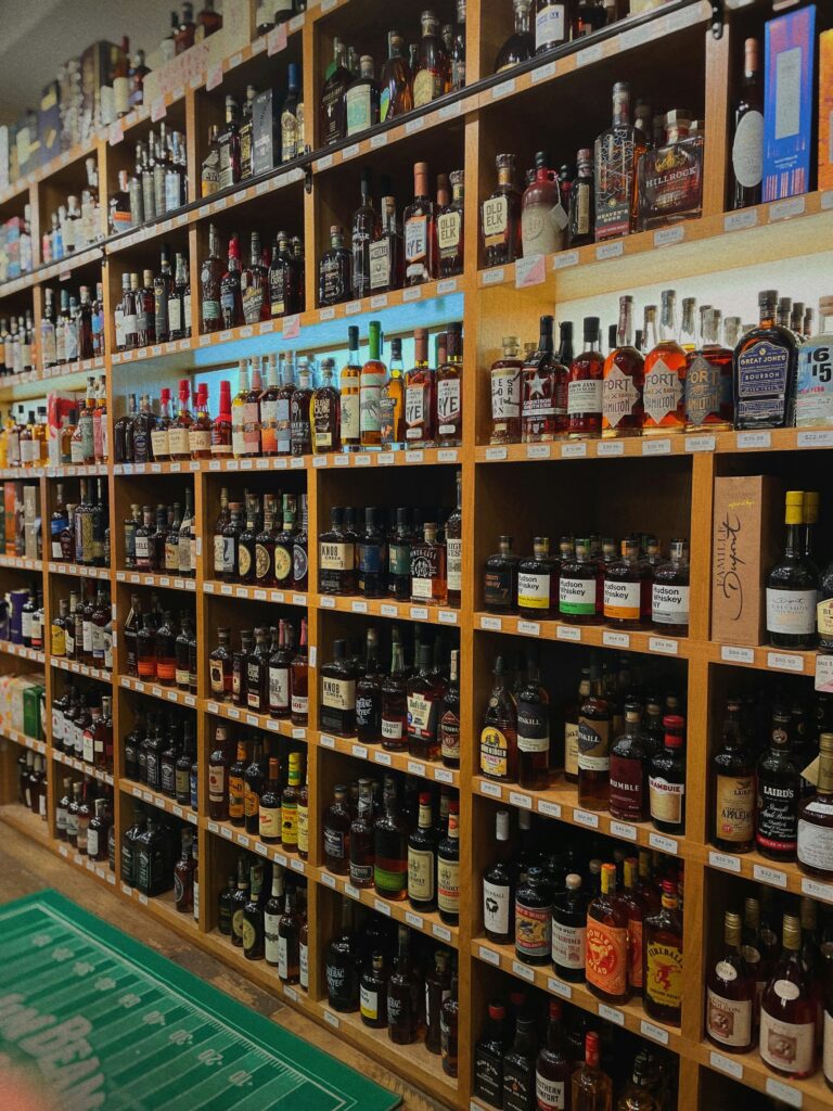 Floor-to-ceiling wooden shelves packed with bottles of bourbon, rye and other American whiskeys in a liquor store.